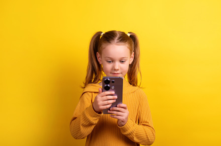 Young girl with pigtails in a mustard sweater holding and lookin
