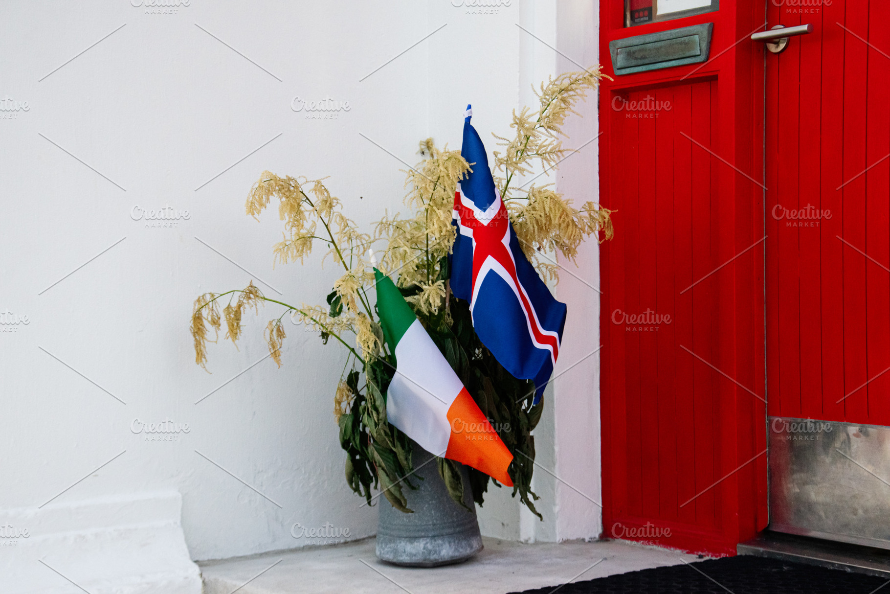 Irish and Icelandic flags displayed outside a vibrant red door in Akranes, Icel, a Photo by AS photostudio