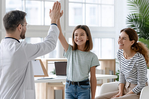 Doctor giving highfive to young girl, a Health & Medical Photo by 7DesignLab