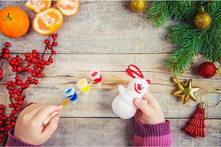 A child paints a Christmas toy, a, a Holiday Photo by yanadjana