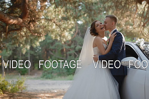 Bride And Groom Pose Near The Car In Pine Wood