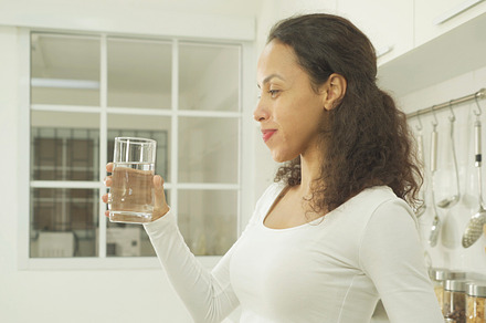 Portrait of happy latin woman drinking a glass of water in kitch, a Person Photo by Tampatra