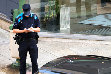 policeman writing fine ticket for car bad parking