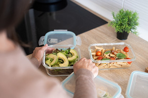 Woman preparing healthy meals in glass food containers.