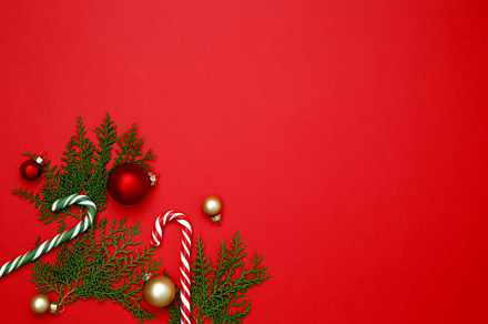 Christmas ornaments, thuja branches, and candy cane arranged on a red backgroun, a Photo by matucha
