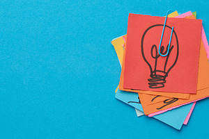 A stack of sticky notes with a light bulb drawn on them is held, a Business Photo by ndanko