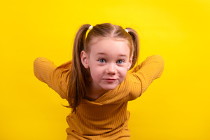 Cheerful young girl with pigtails and mustard yellow sweater pla, a Person Photo by Ales Munt