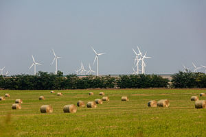 Modern wind turbines overlook a green field scattered with round hay bales unde, a Nature Photo by Ales Munt