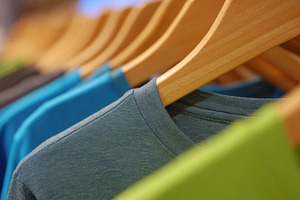 Colorful shirts hang on wooden racks, a Photo by Beautiful things