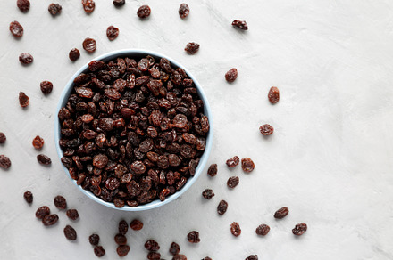 Dried Brown Raisins in a Bowl, top view. Flat lay, overhead, fro, a Food & Drink Photo by LiudmylaChuhunova