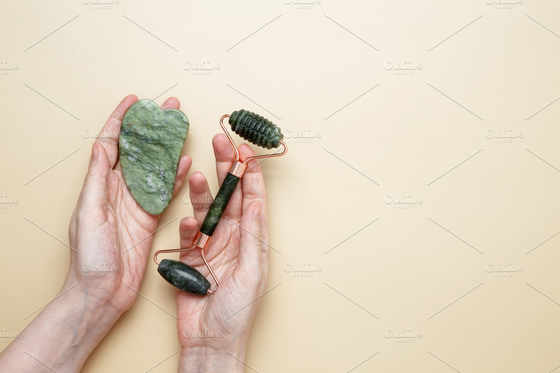 Female hands holding marble face roller and gua sha tools for skincare routine, a Photo by matucha