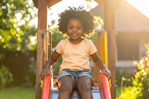 Smiling Child on Playground Slide at Sunset, a Sports & Recreation Photo by Davizro's Market
