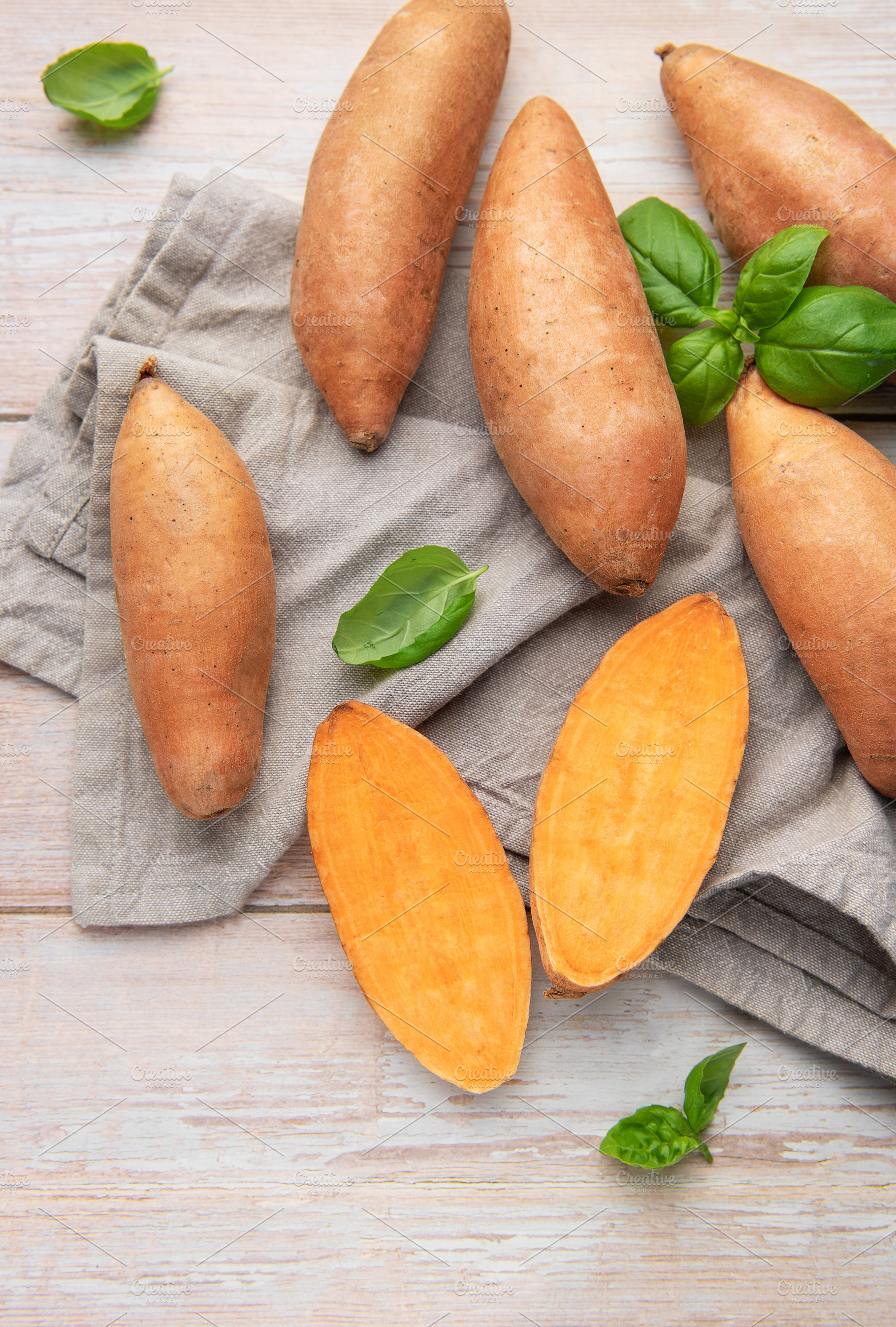 Fresh sweet potatoes and basil on wooden background, a Food & Drink Photo by Olena Rudo