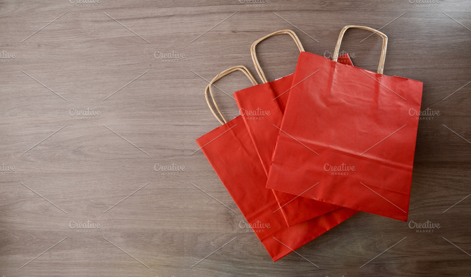 Pack of three red paper shopping bag on wooden table, an Industrial Photo by Davizro's Market
