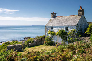 Coastal cottage on cliff overlooking serene blue ocean waters an, a Photo by Studio ANNA