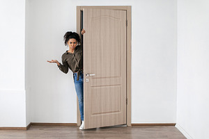 Discontented Black Lady Opening Door Looking At Camera At Home, a Photo by Prostock-Studio