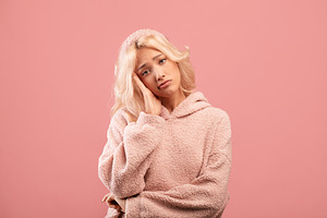 Bored young woman feeling upset and depressed, looking at camera, posing over p, a Photo by Prostock-Studio