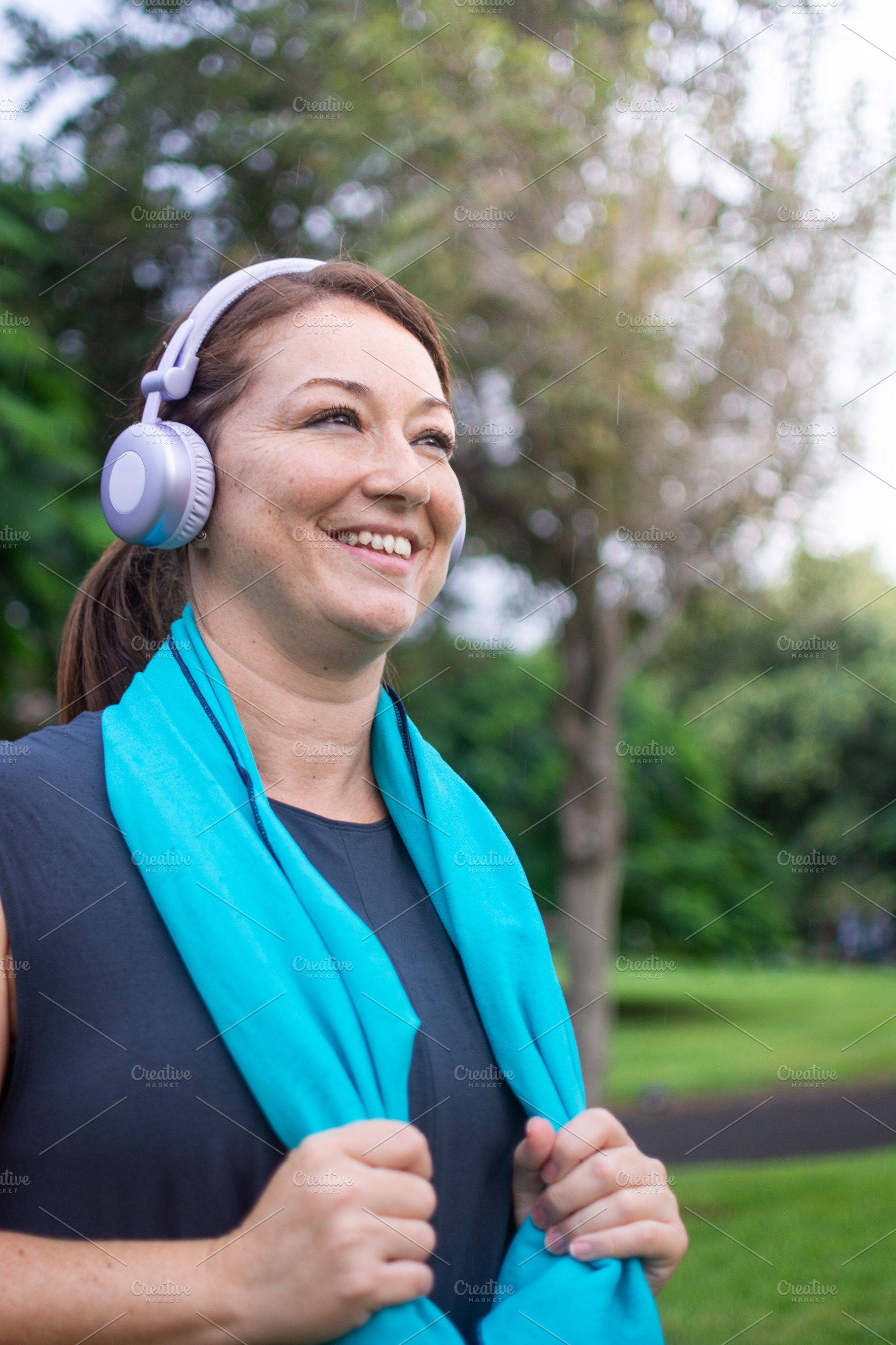 Happy active woman smiling with headphones and towel after outdoor workout, a Photo by etorres69