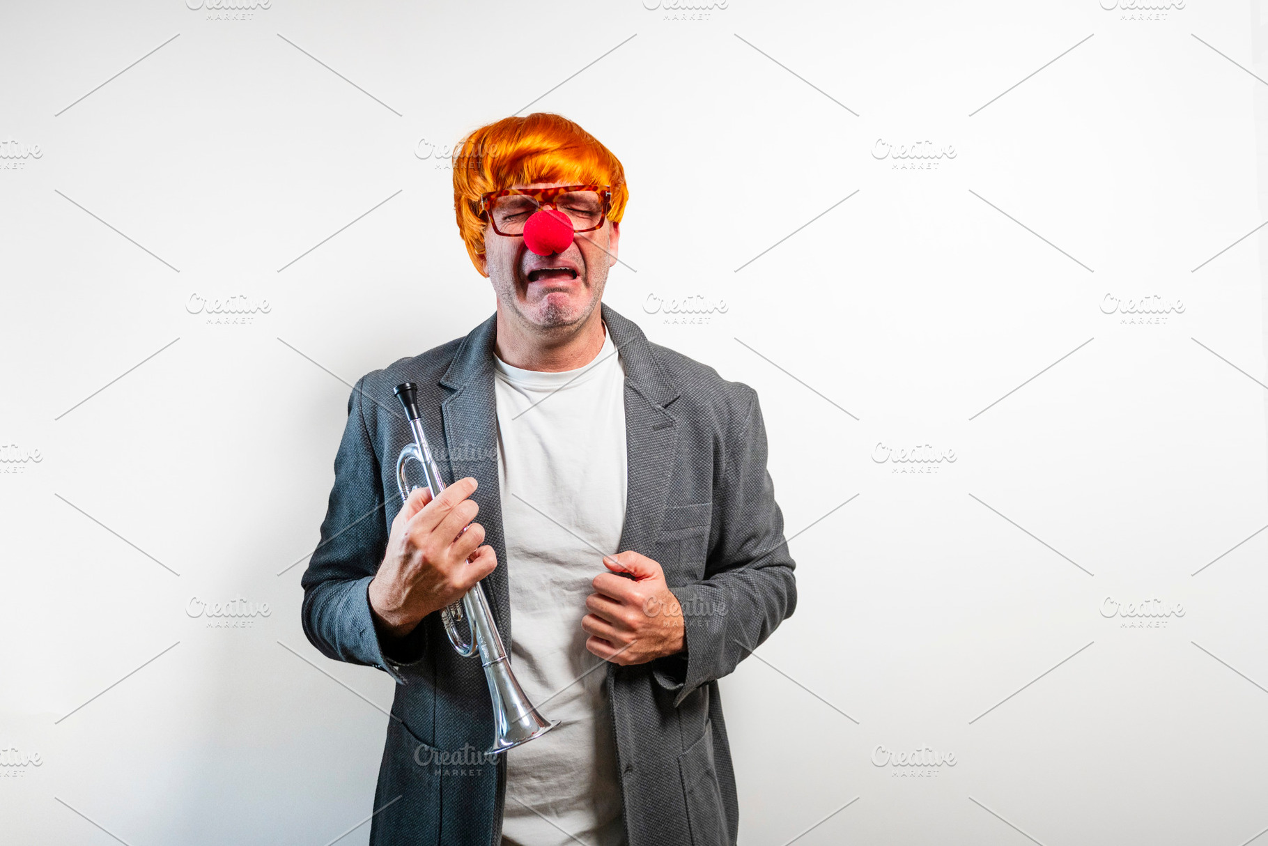 Sad clown man crying while holding a trumpet, a Person Photo by karrastock