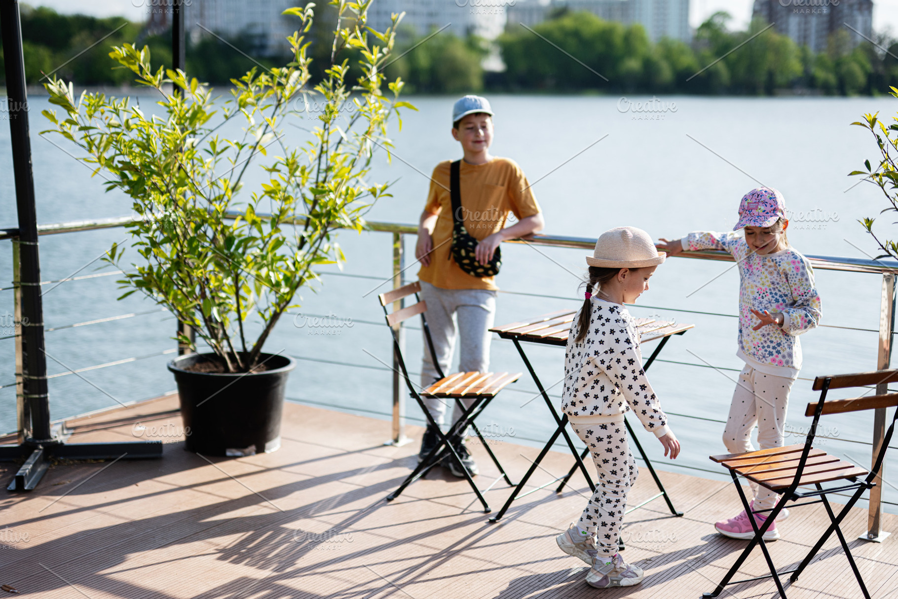 Children enjoying on a terrace by the lake on a sunny day, a Person Photo by AS photostudio