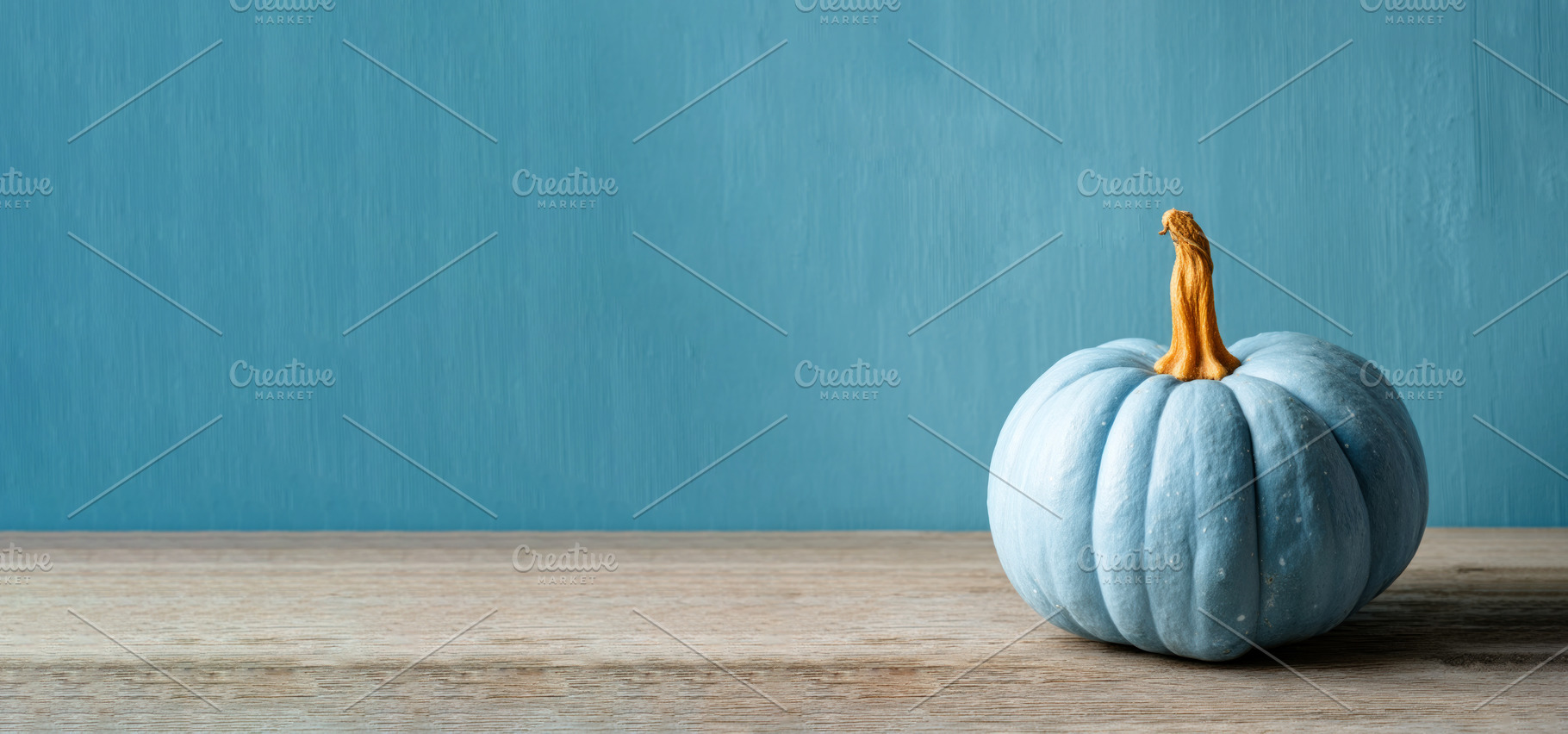 Single blue pumpkin with orange stem on rustic wooden table agai, a Food & Drink Photo by José Manuel Gelpi