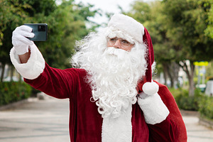 Santa Claus taking a selfie with smartphone outdoors, a Photo by etorres69