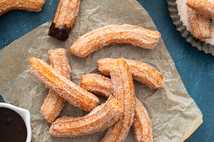 Homemade churros with cinnamon sugar on parchment, a Food & Drink Photo by farwasser