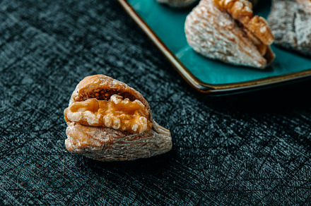 a dried fig filled with half walnut on a table, a Photo by Nito