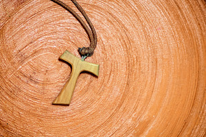 Tau cross pendant resting on a terracotta surface, a Photo by Antonio Gravante Market