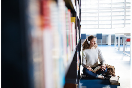Young female student in library, a School & Education Photo by HalfPoint