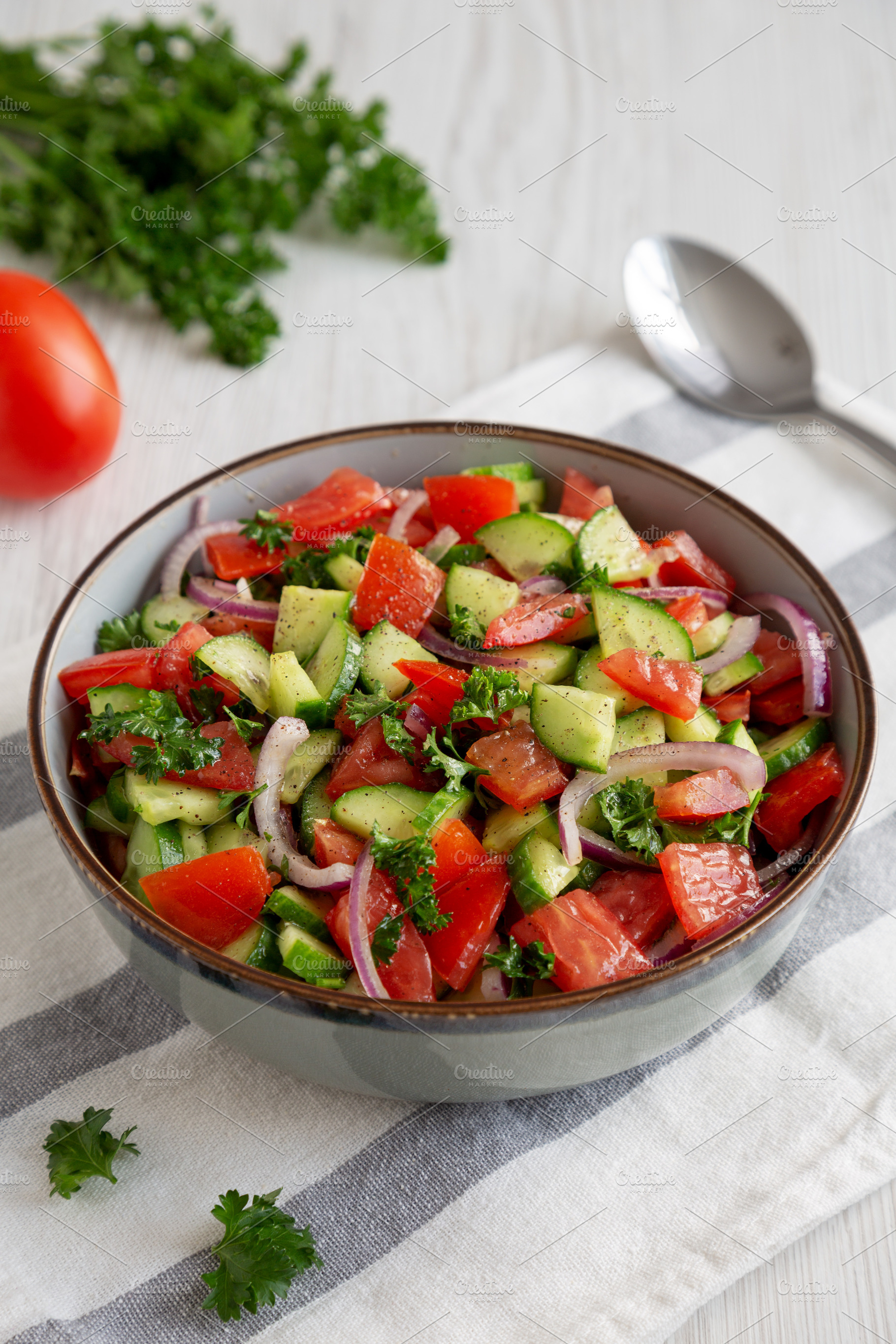 Homemade Mediterranean Cucumber Tomato Salad in a Bowl, side vie, a Food & Drink Photo by LiudmylaChuhunova