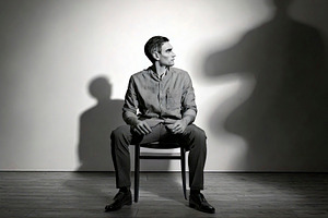 Person sitting alone on a chair with in an empty room at backgro, a Health & Medical Photo by DanFLCreativo