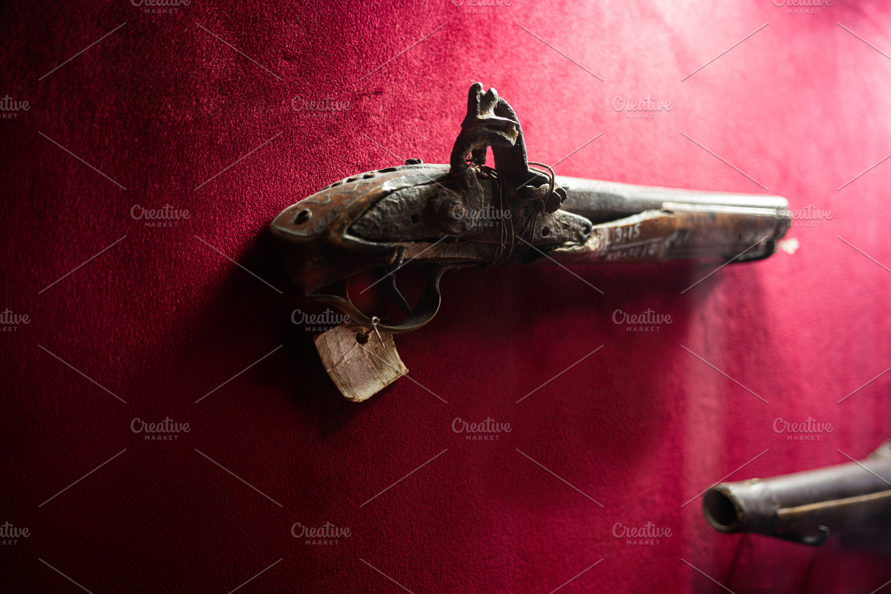 Vintage antique musket displayed against a vibrant red backdrop in close view, a Photo by AS photostudio