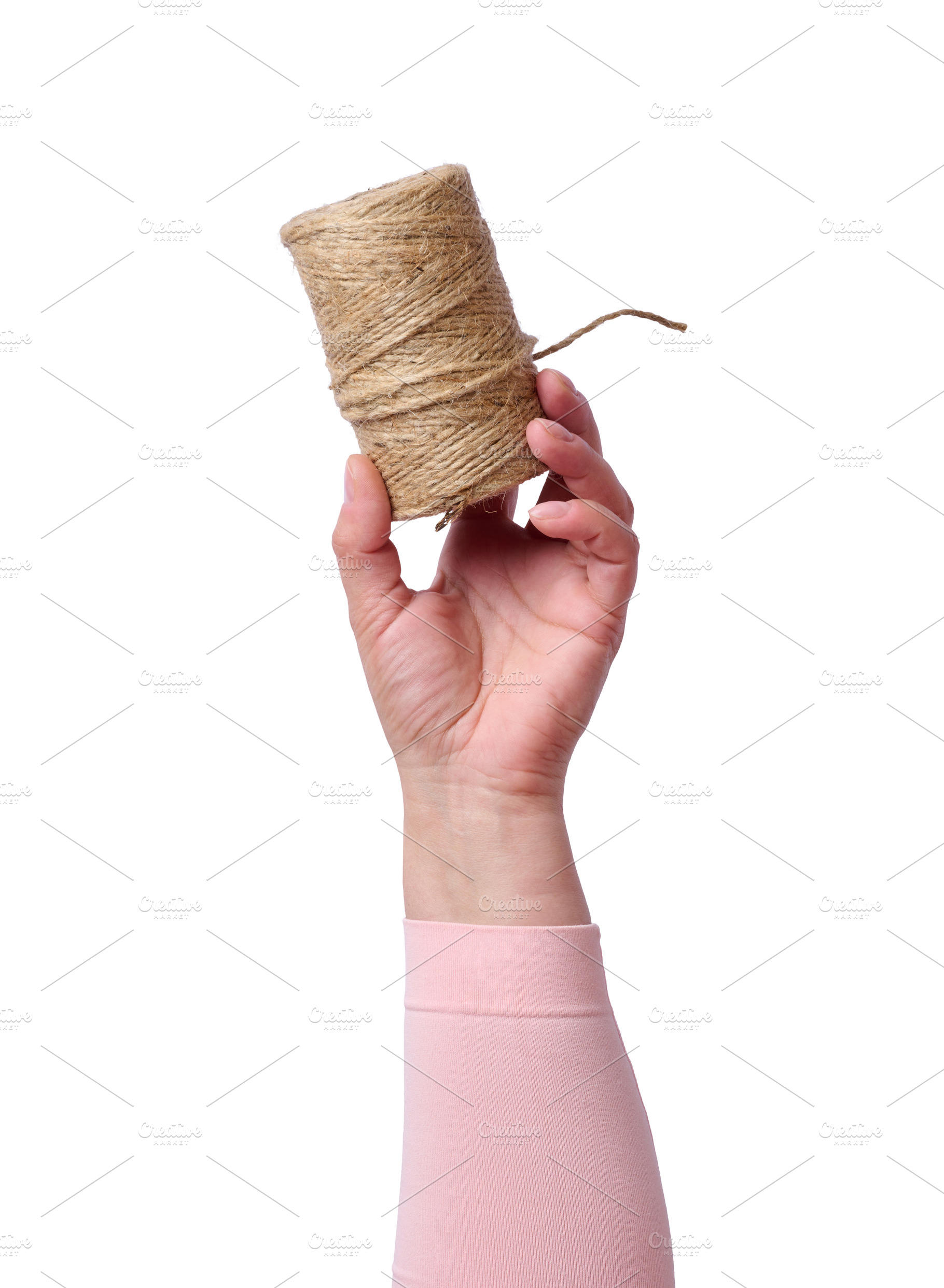 A woman's hand in a pink sleeve holds a jute rope in a skein on, a Person Photo by ndanko