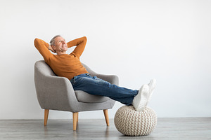 Mature man having rest at home on the chair, a Photo by Prostock-Studio