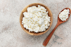 Cottage cheese in wooden bowl with spoon, a Food & Drink Photo by Olena Rudo