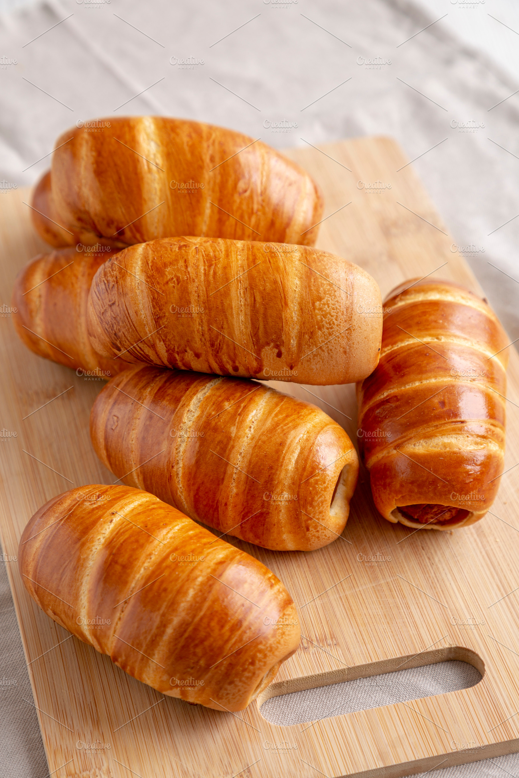 Homemade Sausage Buns on a bamboo board, side view., a Food & Drink Photo by LiudmylaChuhunova