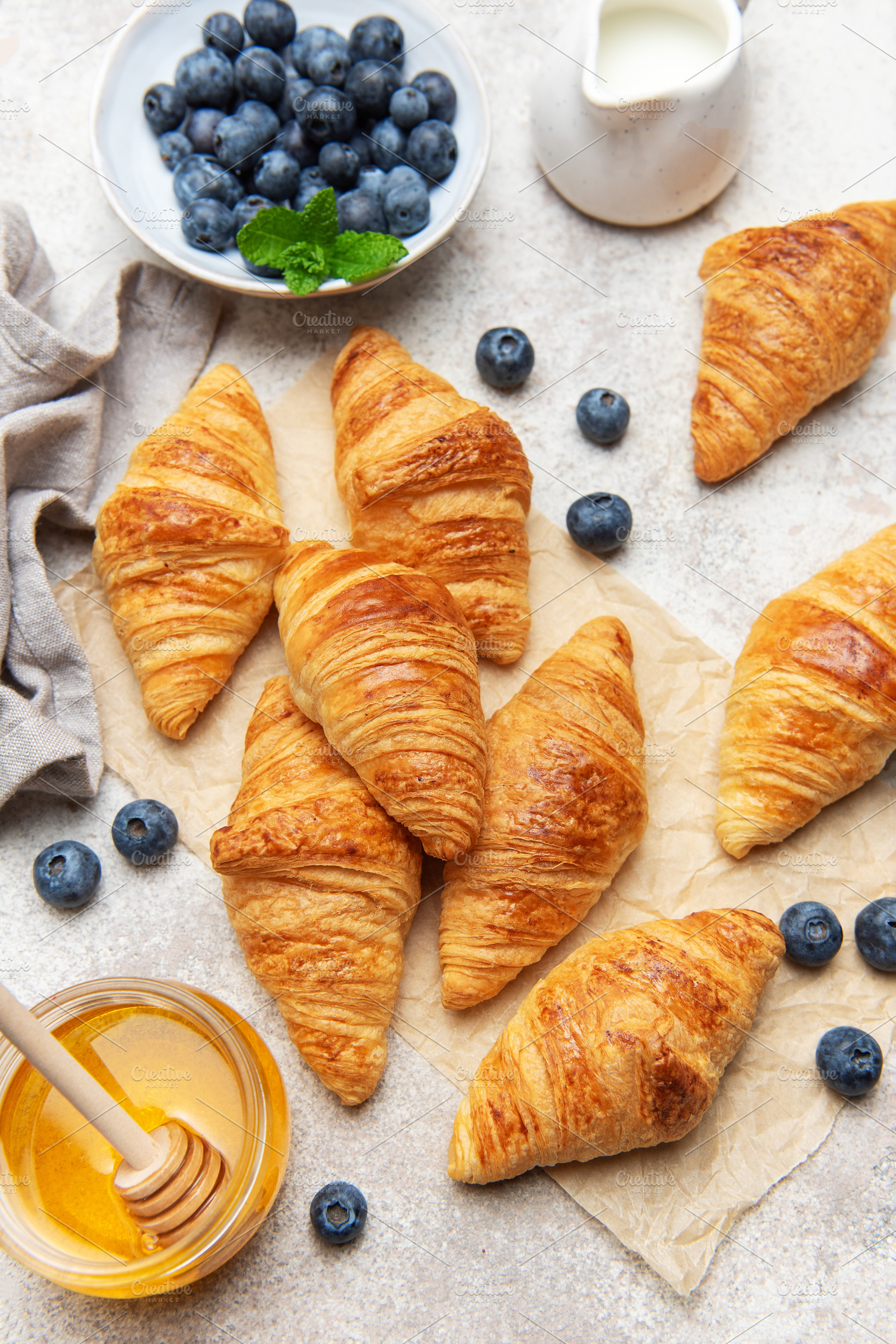 Freshly baked croissants with honey, blueberries, and milk for b, a Food & Drink Photo by Olena Rudo