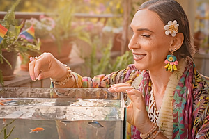 Transgender woman feeding fish on a sunny balcony, a Person Photo by DanFLCreativo