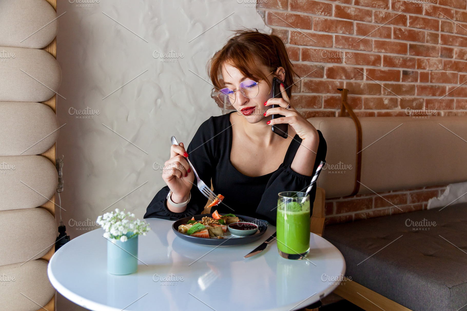 Woman talking on phone while eating healthy lunch in cafe, a Person Photo by Photostock