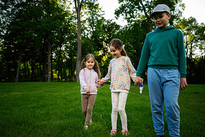 Children holding hands outdoors in a green field on a sunny day, a Person Photo by AS photostudio