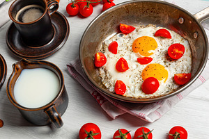 Delicious breakfast with fried eggs and cherry tomatoes in a pan, coffee and mi, a Food & Drink Photo by Antonio Gravante Market