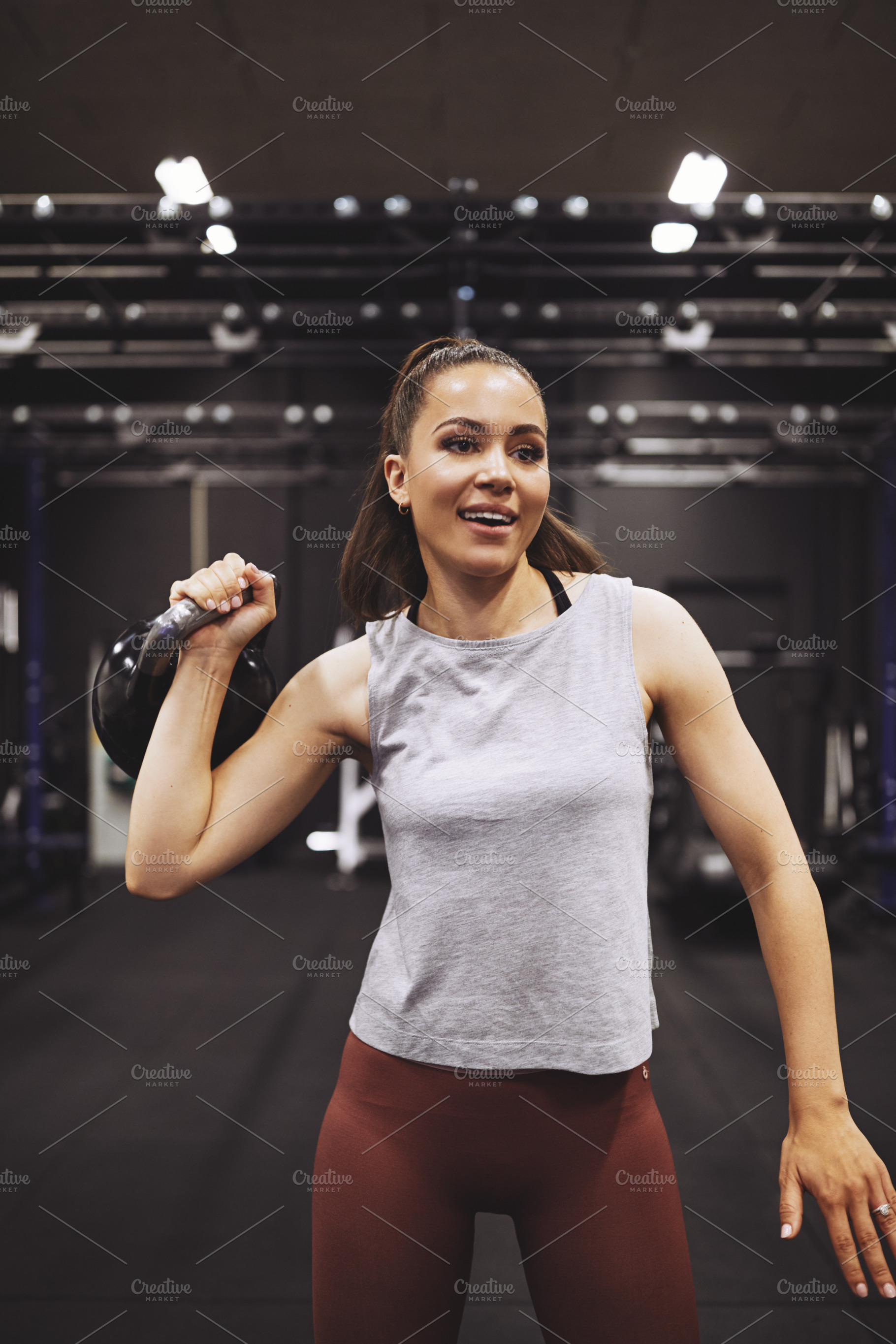 Smiling young woman lifting a dumbbell at the gym, a Sports & Recreation Photo by Stefan & Janni