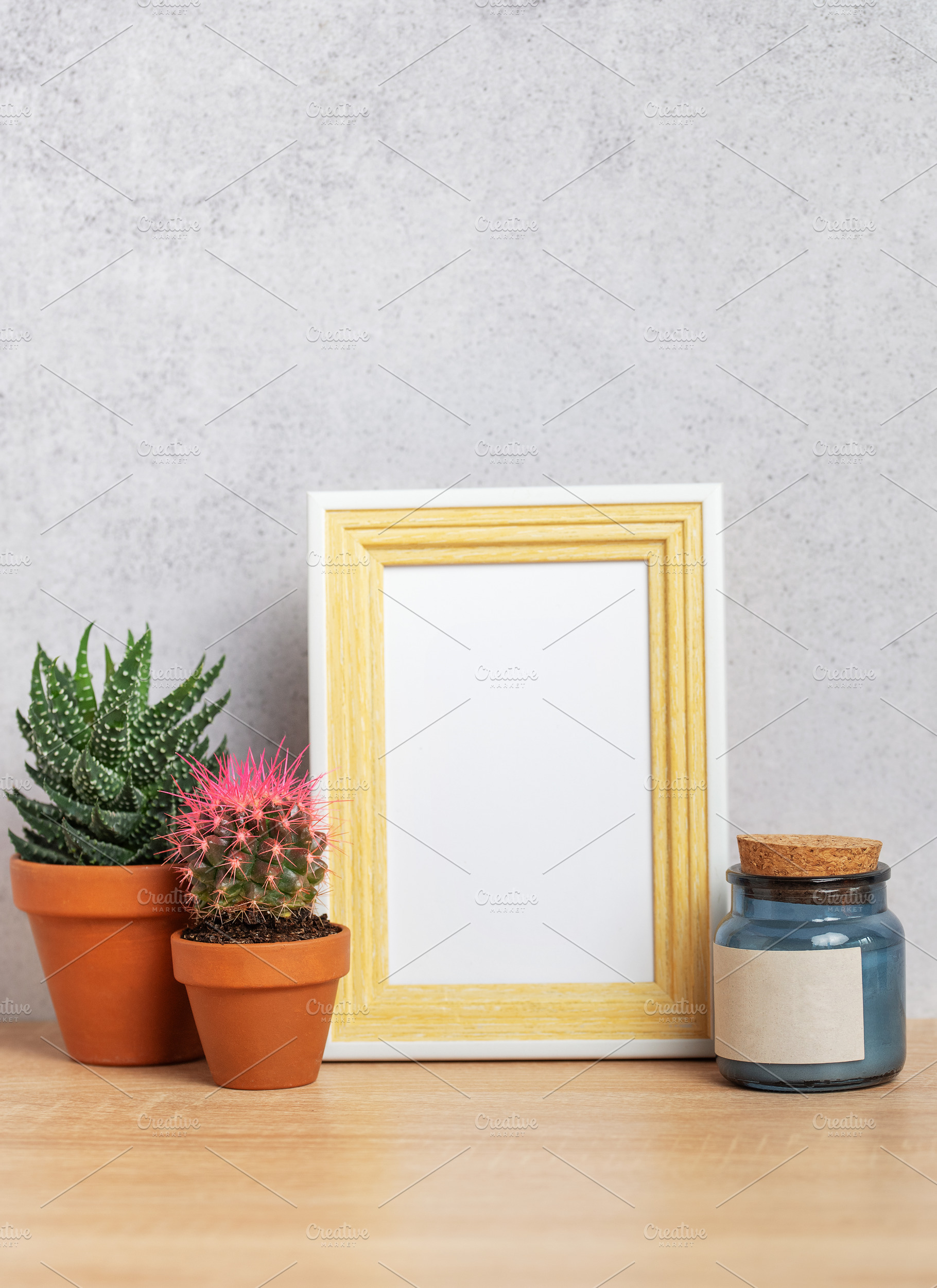 Empty photo frame with cacti, candle and copy space on wooden ta, a Business Photo by Olena Rudo