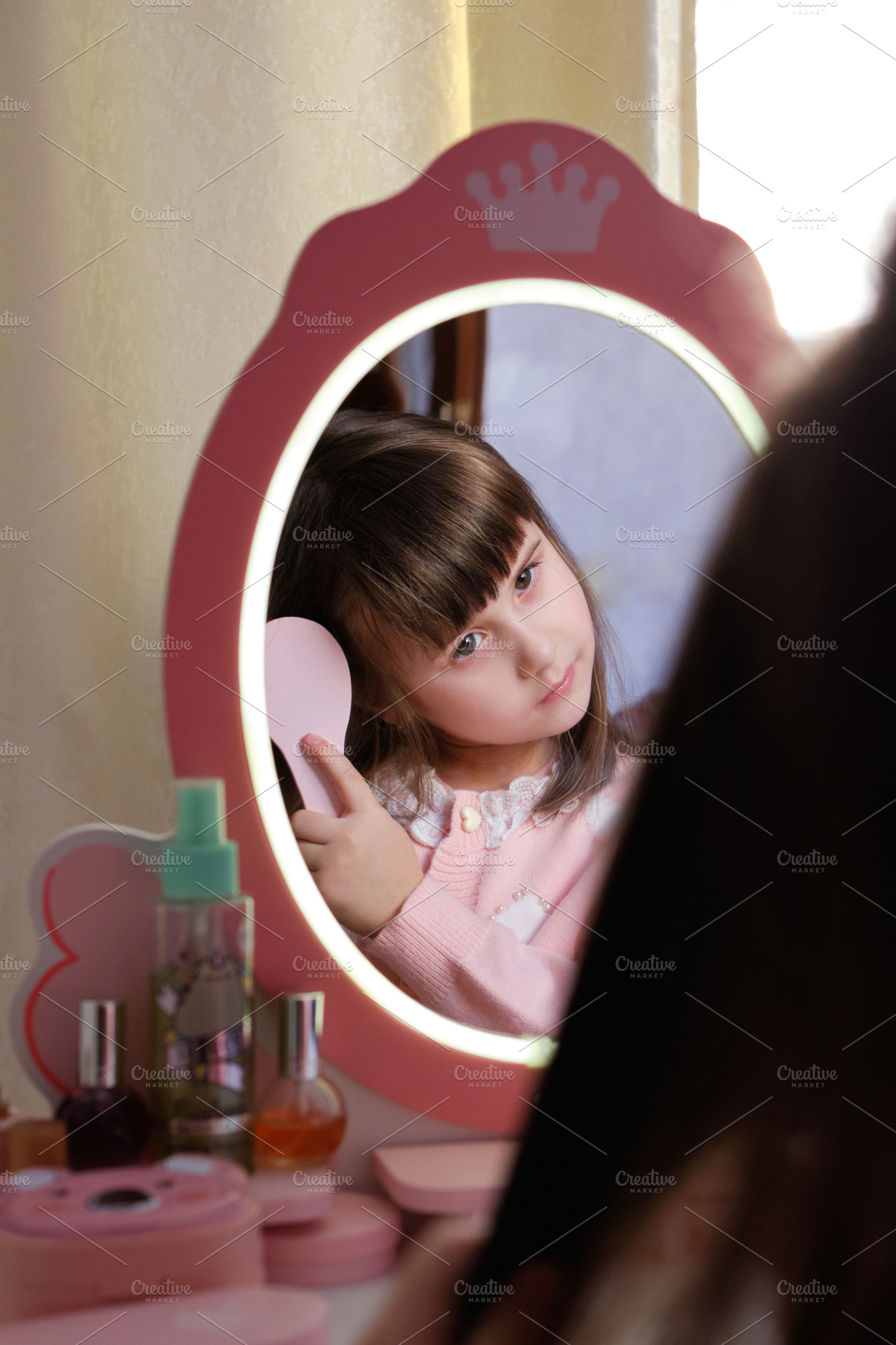 Little girl brushing her hair looking in a toy mirror with LED lights., a Person Photo by Rohan Photography