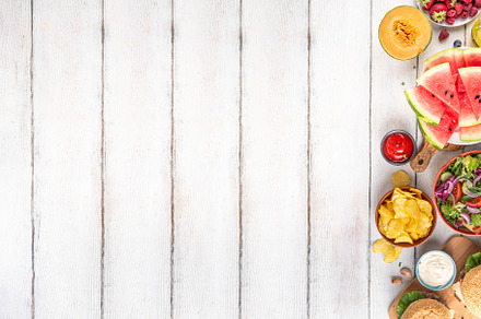 Tasty summer barbecue table with hamburgers, salads, fruits and