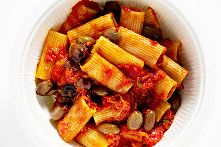 Italian tortiglioni pasta puttanesca with tomato sauce and black