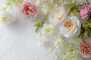Beautiful flowers and green leaves framing a white textured back, a Photo by Studio ANNA