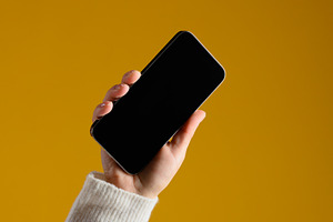 A man's hand in a white sweater holds a modern smartphone with a, a Technology Photo by ndanko