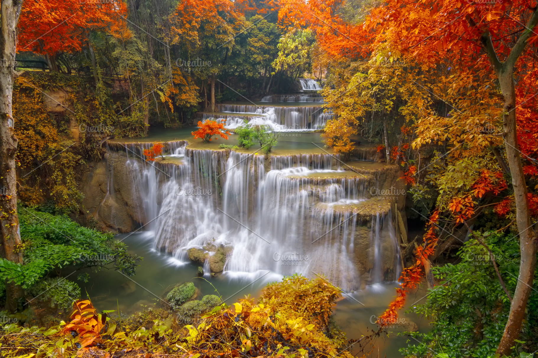 Waterfall in colorful autumn forest featuring thailand, kanchanaburi, and tree, a Nature Photo by Love Silhouette